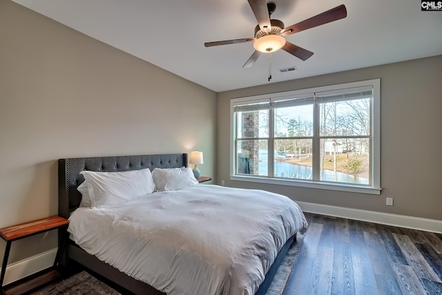 bedroom featuring dark wood finished floors, visible vents, a ceiling fan, vaulted ceiling, and baseboards