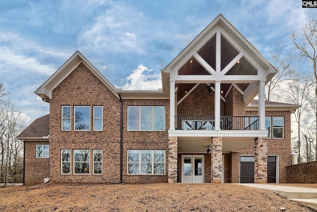 view of front of property featuring driveway, a garage, a balcony, french doors, and brick siding