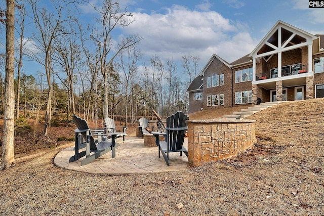 view of yard featuring a fire pit, a patio area, and a balcony