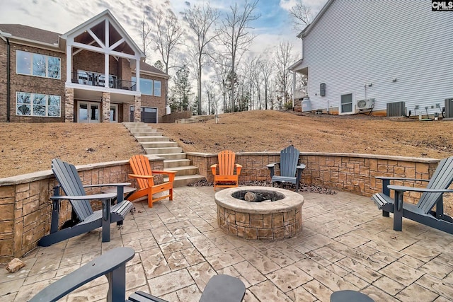 view of patio with a fire pit, central AC, stairs, and a balcony