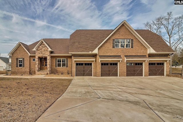 view of front of property featuring a garage, brick siding, driveway, and roof with shingles