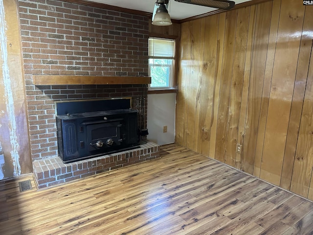 unfurnished living room with visible vents, wooden walls, and wood finished floors