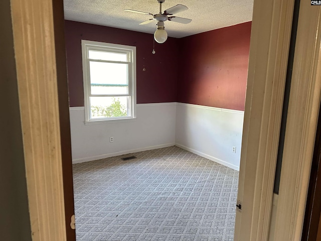 carpeted spare room with a textured ceiling, ceiling fan, visible vents, and baseboards