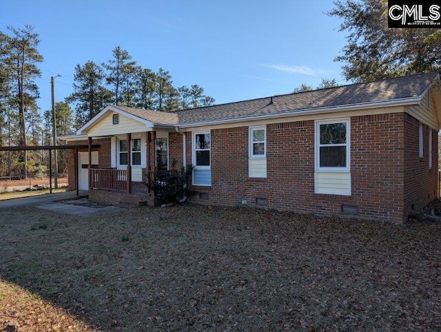 view of front of house with brick siding, roof with shingles, covered porch, crawl space, and an attached carport