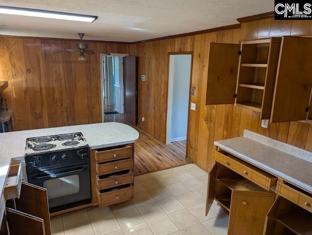 kitchen with electric range, ceiling fan, brown cabinets, crown molding, and wood walls