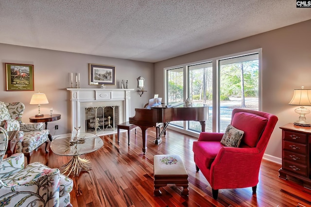 sitting room with hardwood / wood-style flooring, a fireplace, baseboards, and a textured ceiling