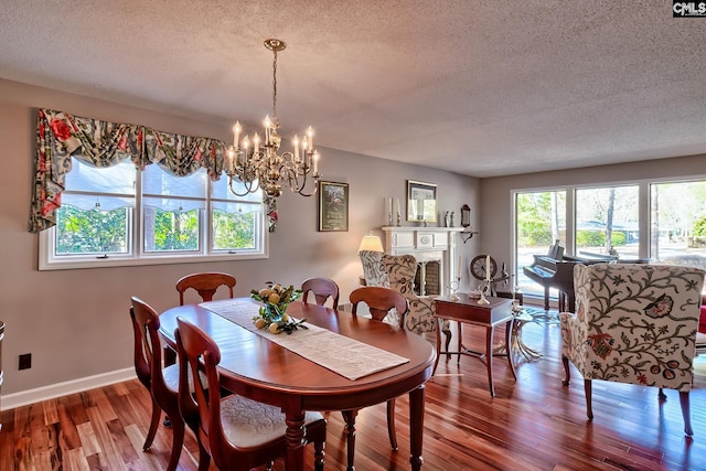 dining space featuring a chandelier, a textured ceiling, baseboards, and wood finished floors