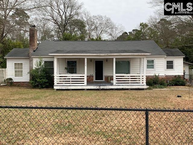 view of front of property with covered porch, a chimney, a front yard, and fence