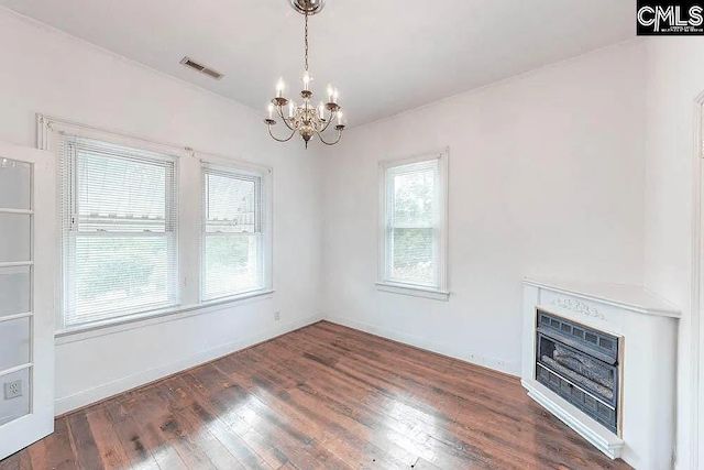 interior space featuring a notable chandelier, a fireplace, visible vents, heating unit, and wood-type flooring