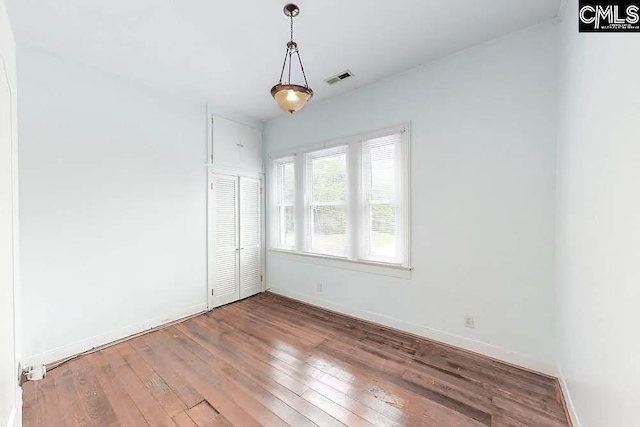 unfurnished room featuring hardwood / wood-style flooring, visible vents, and baseboards