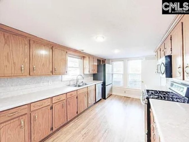 kitchen with a sink, stainless steel appliances, light wood finished floors, and light countertops