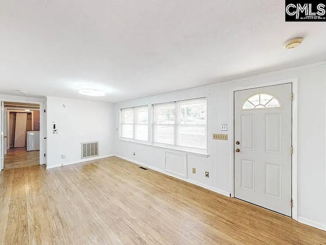 foyer featuring light wood finished floors, baseboards, and visible vents