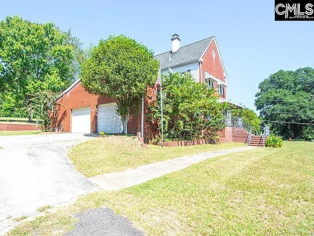 view of front of property with brick siding, a detached garage, a chimney, and a front yard