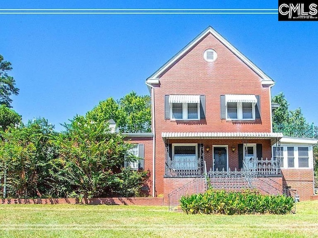 view of front of property with covered porch, a front lawn, and brick siding