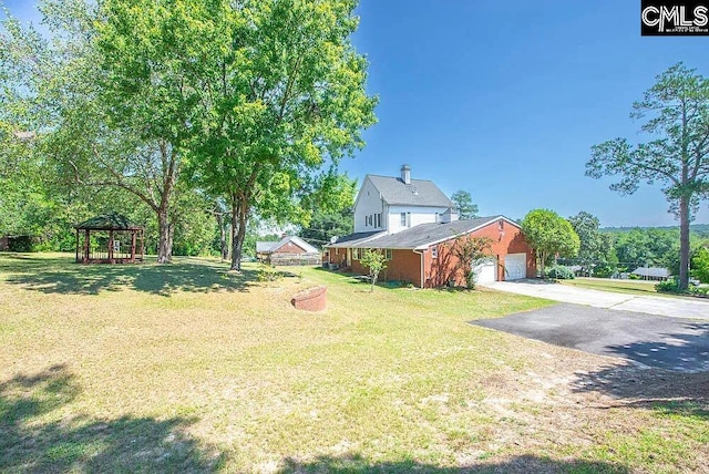 view of yard featuring a garage, driveway, and a gazebo