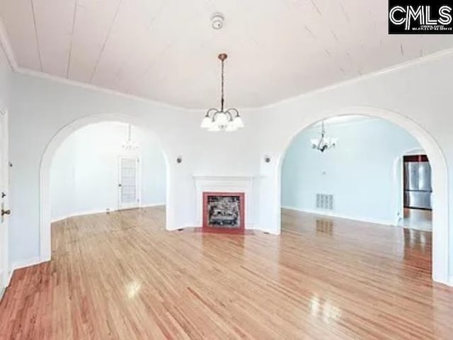 unfurnished living room with a notable chandelier, a fireplace, visible vents, light wood-style floors, and ornamental molding