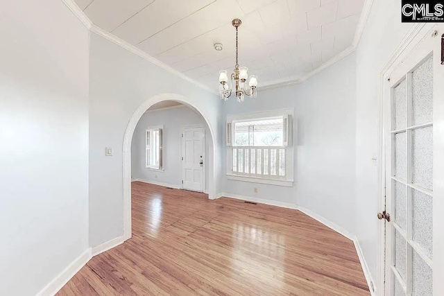 interior space featuring baseboards, light wood-style flooring, arched walkways, and crown molding