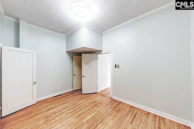 empty room featuring visible vents, ornamental molding, light wood-style flooring, and baseboards