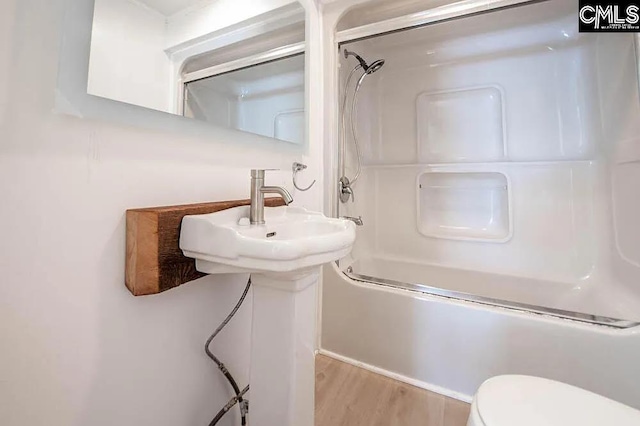 bathroom with shower / bath combination, toilet, and wood finished floors