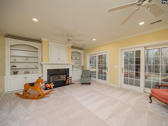 sitting room with ornamental molding, light colored carpet, visible vents, and a fireplace with flush hearth