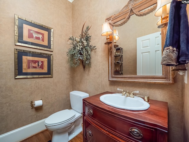 bathroom with toilet, baseboards, wood finished floors, and vanity