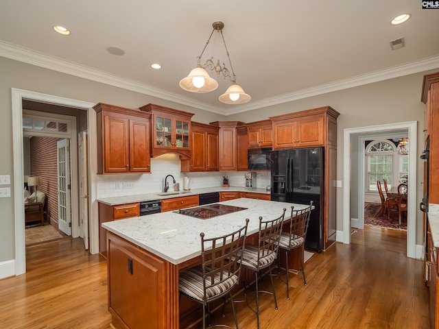 kitchen featuring a breakfast bar area, a center island, light wood-style flooring, and black appliances