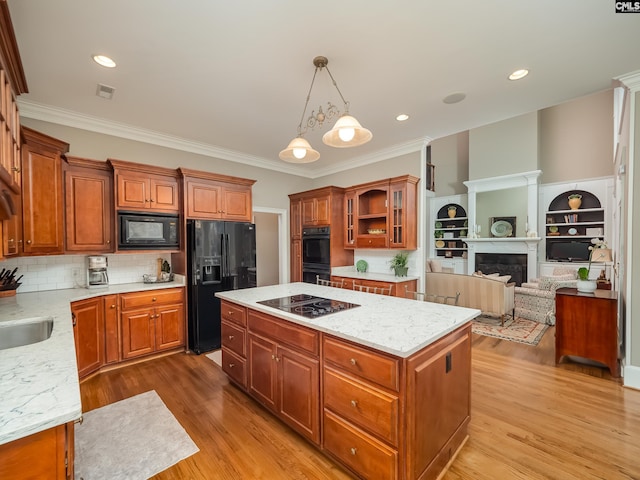 kitchen featuring black appliances, a fireplace, light wood-style flooring, and a center island