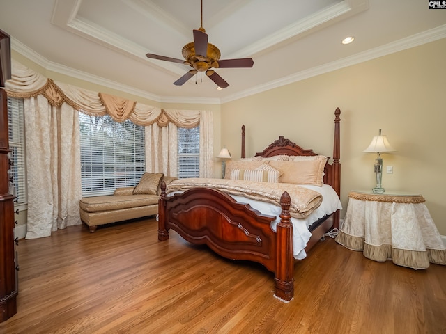 bedroom featuring a tray ceiling, wood finished floors, and crown molding