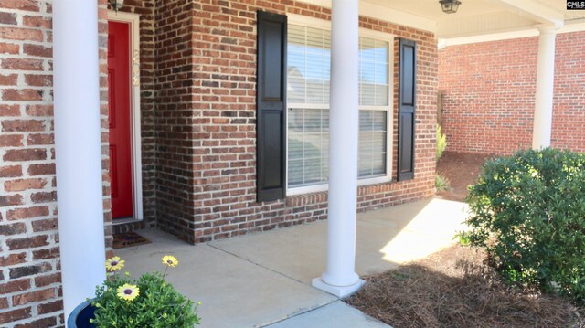 entrance to property with a porch and brick siding