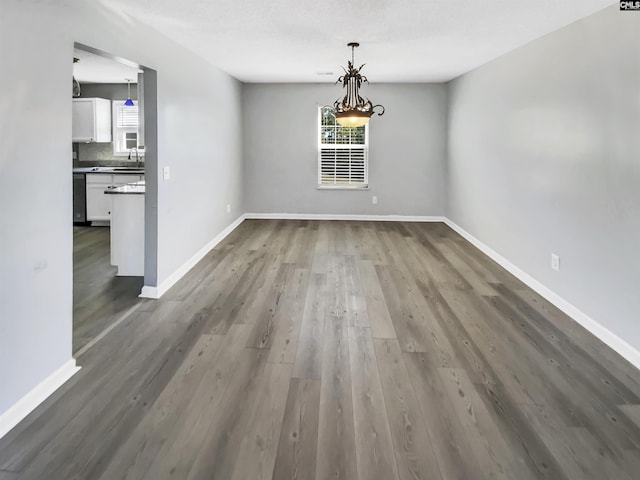 unfurnished dining area featuring a sink, baseboards, and dark wood-style floors