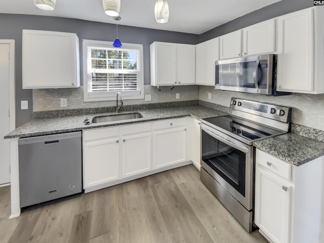 kitchen featuring tasteful backsplash, white cabinetry, stainless steel appliances, and a sink