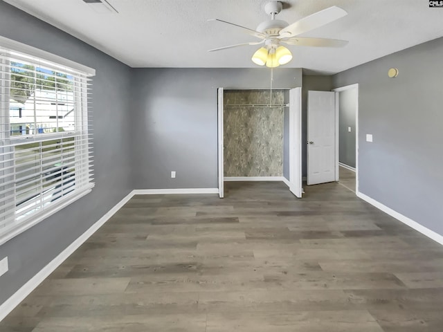 unfurnished bedroom featuring a ceiling fan, visible vents, wood finished floors, baseboards, and a closet