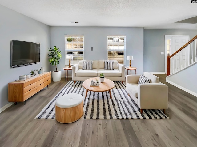 living area with visible vents, baseboards, wood finished floors, and stairs