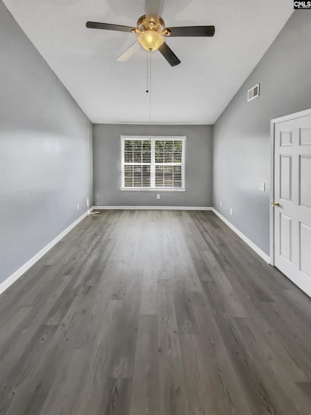 empty room featuring visible vents, baseboards, wood finished floors, and vaulted ceiling