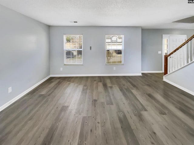 interior space featuring visible vents, a textured ceiling, wood finished floors, baseboards, and stairs