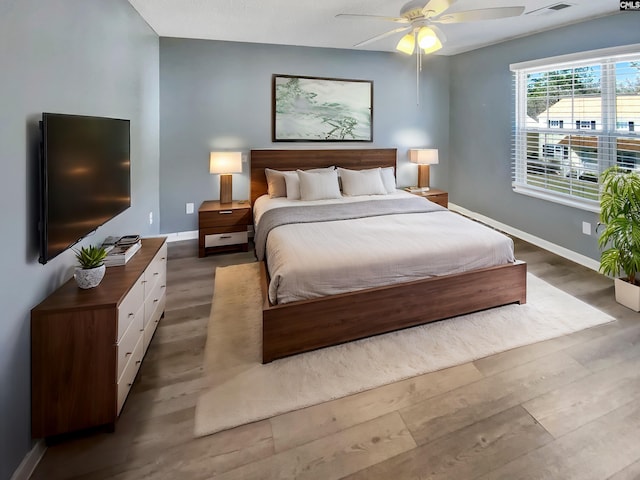 bedroom featuring visible vents, ceiling fan, baseboards, and wood finished floors