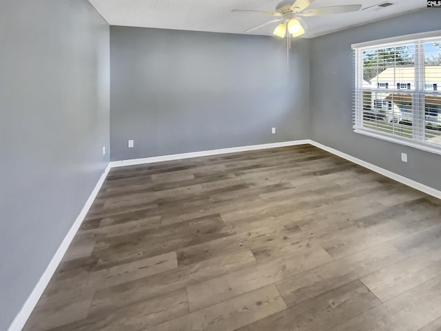 empty room with ceiling fan, visible vents, baseboards, and wood finished floors