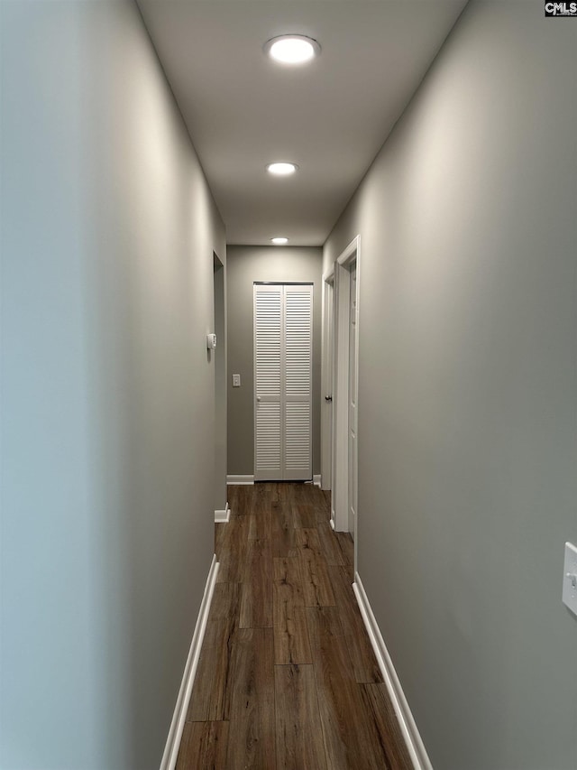 corridor featuring baseboards and dark wood-style flooring