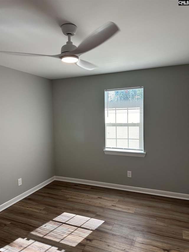 unfurnished room featuring dark wood finished floors, a ceiling fan, and baseboards