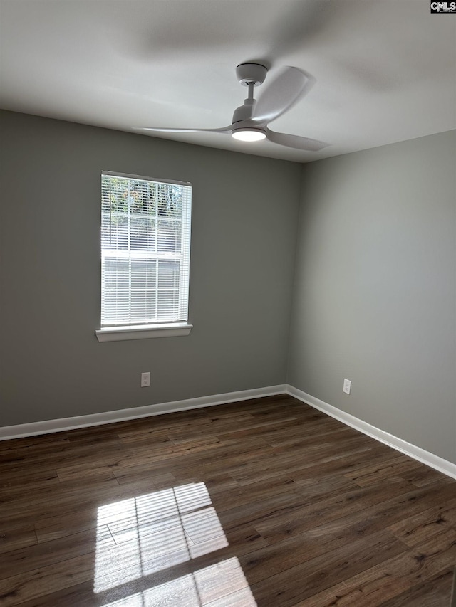 unfurnished room with baseboards, dark wood finished floors, and a ceiling fan