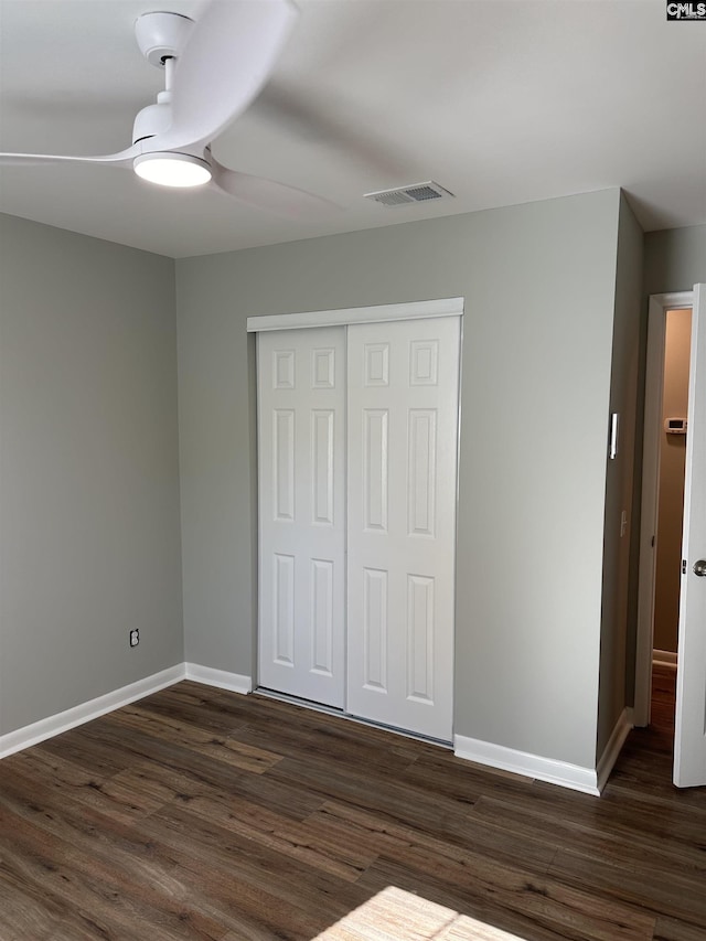 unfurnished bedroom featuring dark wood finished floors, visible vents, baseboards, and a closet