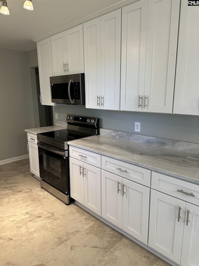 kitchen featuring white cabinetry, light stone counters, baseboards, and appliances with stainless steel finishes