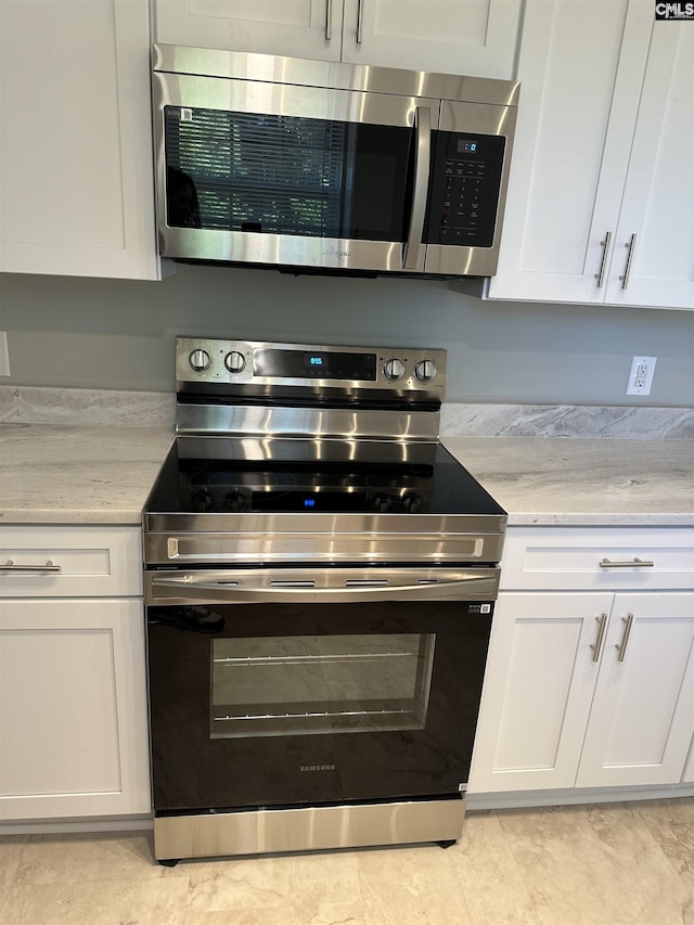 kitchen with white cabinetry, stainless steel appliances, and light stone countertops