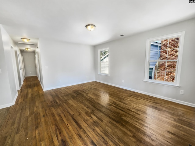 spare room featuring baseboards and dark wood finished floors