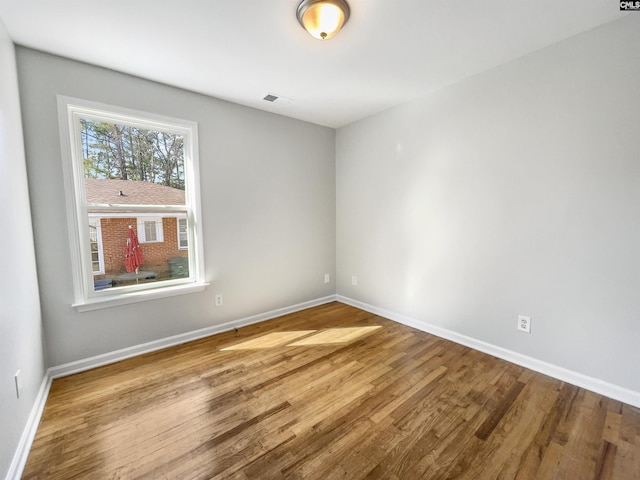 spare room featuring visible vents, baseboards, and wood finished floors