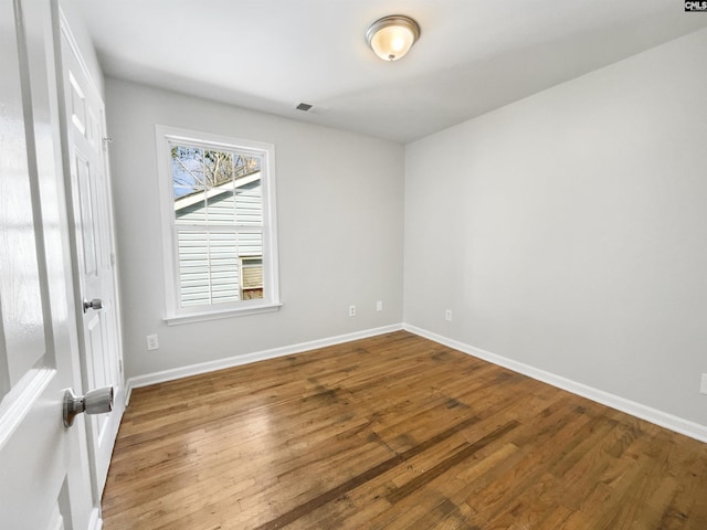 empty room featuring visible vents, baseboards, and wood finished floors