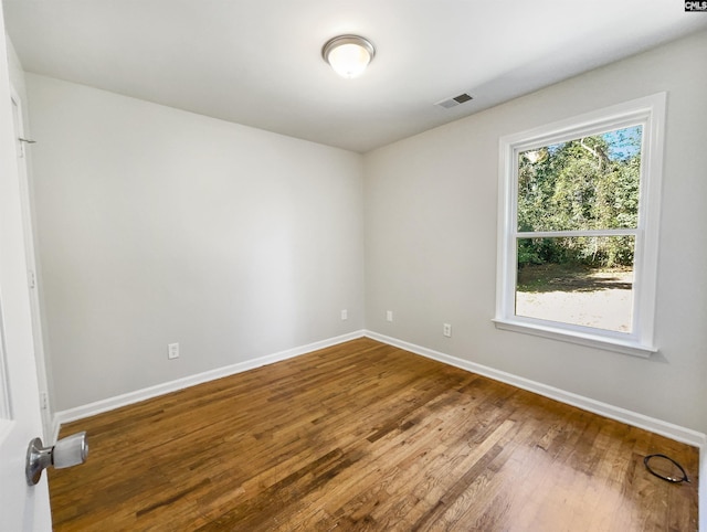 unfurnished room featuring wood finished floors, visible vents, and baseboards