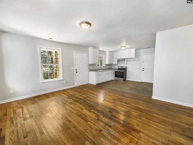 kitchen with dark wood finished floors, white cabinetry, stainless steel electric range oven, and baseboards