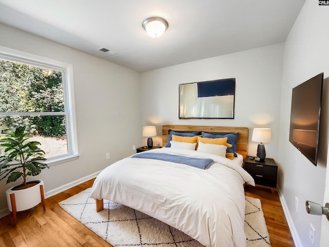 bedroom featuring visible vents, baseboards, and wood finished floors