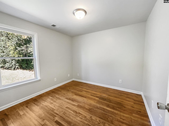 spare room with visible vents, baseboards, and wood finished floors